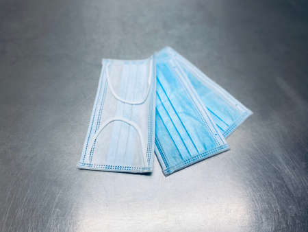 virus, three layer,  blue and white, disposable, surgical face masks, on a stainless steel hospital...