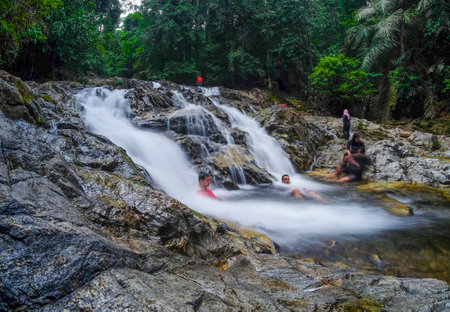 KENYIR LAKE, MALAYSIA - AUGUST 25, 2016 : Tourist enjoy the beautiful nature landscape of Saok Waterfall, Kenyir Lake, Terengganu, Malaysia. Saok Waterfall also known as Air Terjun Saok.のeditorial素材