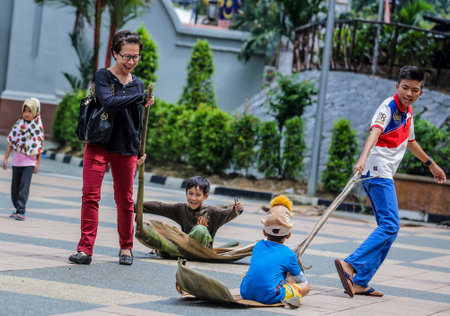 KUALA LUMPUR, MALAYSIA - DECEMBER 17, 2016 : Kids playing traditional game 'Tarik Upih Pinang' or Palm Frond Sledding.のeditorial素材