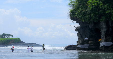 BALI, INDONESIA - NOVEMBER 15, 2017 : Balinese people in traditional clothes walk crossing the sea during religious ceremony at Tanah Lot temple, Bali.のeditorial素材