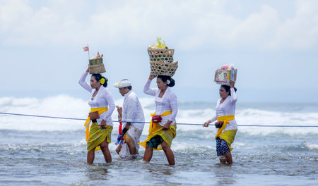 BALI, INDONESIA - NOVEMBER 15, 2017 : Balinese people in traditional clothes walk crossing the sea during religious ceremony at Tanah Lot temple, Bali.のeditorial素材