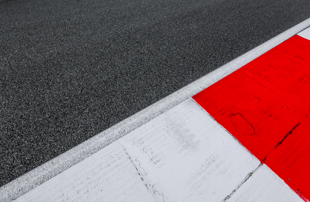 Asphalt red and white kerb of a race track detail. Motorsports racing circuit close up.の写真素材