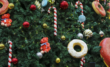 Close up of Christmas tree decorations with ornaments of baubles, candy cane, sweet donut, and lights. Merry Christmas and Happy Holidays.の写真素材