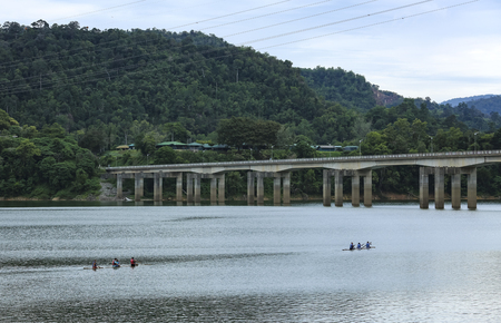 Tourist sitting and standing on the bamboo raft while discover peace environment of Royal Belum Rainforest acrossing the Temenggor Lake at Pulau Banding, Perak.の写真素材