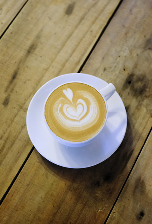 Cups of cafe latte on wooden table background. Art style hot coffee. A latte is a coffee drink made with espresso and steamed milk.の写真素材