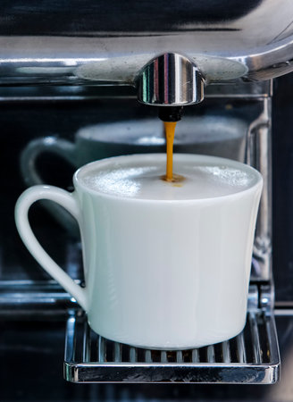 Close-up of espresso pouring from coffee machine to make latte.のeditorial素材