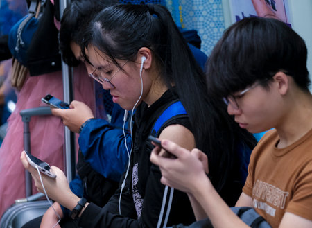 KUALA LUMPUR, MALAYSIA - FEBRUARY 22, 2020 : Passenger using mobile phone in Mass Rapid Transit (MRT) train to browsing web, listening music, playing games, texting and browsing social media.のeditorial素材