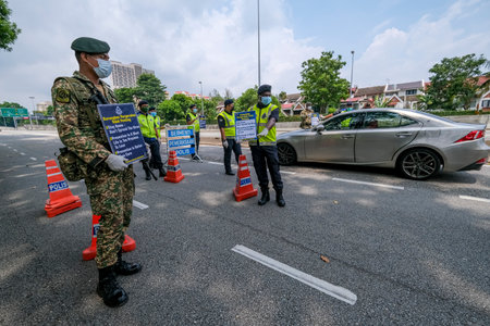 KUALA LUMPUR, MALAYSIA - MARCH 22, 2020 : Malaysia soldier and police inspect road users at a roadblock to enforce the order to stay at home, during the 'movement control order' COVID-19 outbreak.のeditorial素材