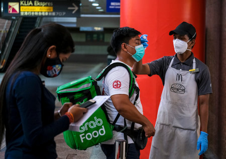 KUALA LUMPUR, MALAYSIA - MARCH 22, 2020: People wearing a face mask and check the body temperature to prevent infection of the virus. Coronavirus disease 2019 (COVID-19) outbreak.のeditorial素材