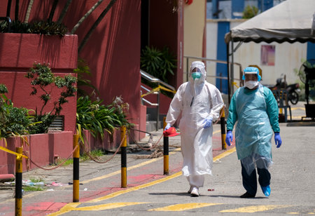 KUALA LUMPUR, MALAYSIA - APRIL 19, 2020: Health workers wearing a protective suit walk after entering COVID-19 red zone. Coronavirus disease 2019 (COVID-19) outbreak.のeditorial素材