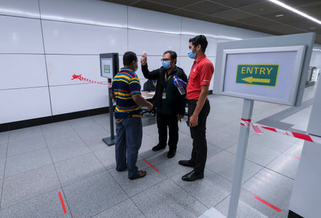 KUALA LUMPUR, MALAYSIA - MAY 5, 2020: A passenger has their body temperatures checked and using hand...