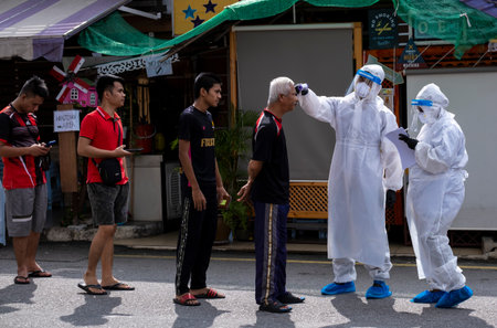 KUALA LUMPUR, MALAYSIA - MAY 06, 2020: A Government health worker wearing a protective suit check body temperatures of foreign workers before do the COVID-19 test. Coronavirus disease 2019 outbreak.のeditorial素材