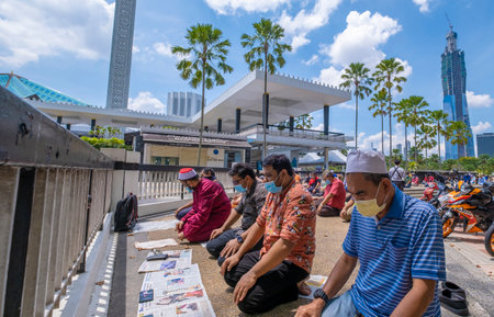 KUALA LUMPUR, MALAYSIA - MAY 15, 2020: Muslims pray outside the National Mosque, after reached its restricted capacity, for the first Friday prayers during Ramadhan due to the COVID-19 lockdown.のeditorial素材