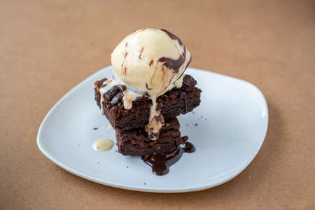Chocolate brownies with vanilla ice cream on white plate. Delicious dessert.