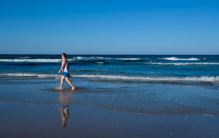 GOLD COAST, AUSTRALIA - APRIL 16, 2018: A man walking enjoying the glories weather and wonderful beaches at Surfers Paradise. One of the main tourist destination at Gold Coast.のeditorial素材