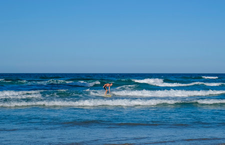 GOLD COAST, AUSTRALIA - APRIL 16, 2018: Surfers surfing and enjoying the glories weather at Main Beach, Surfers Paradise. One of the main tourist destination at Gold Coast.のeditorial素材
