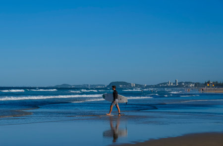 GOLD COAST, AUSTRALIA - APRIL 16, 2018: Surfers carrying surfing boards on Main Beach at Surfers Paradise. One of the main tourist destination at Gold Coast.のeditorial素材