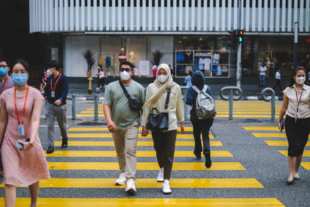KUALA LUMPUR, MALAYSIA - AUGUST 03, 2022: People walking across a busy crosswalk in downtown.のeditorial素材