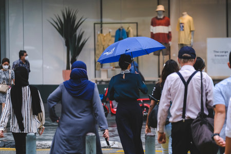 KUALA LUMPUR, MALAYSIA - AUGUST 03, 2022: People walking across a busy crosswalk in downtown.