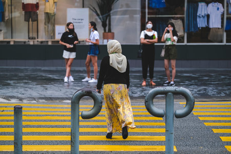 KUALA LUMPUR, MALAYSIA - AUGUST 03, 2022: People walking across a busy crosswalk in downtown.のeditorial素材
