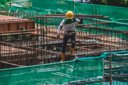 KUALA LUMPUR, MALAYSIA - MARCH 28, 2023: Construction workers wearing safety protective equipment while working on high-rise buildings at the construction site. Economy and development.のeditorial素材