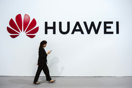 KUALA LUMPUR, MALAYSIA - SEPTEMBER 27, 2023: Women walk past Huawei logo. 5G network, fast-speed...