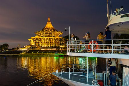 SARAWAK, MALAYSIA - SEPTEMBER 16, 2023: Sarawak River Cruise boat with a background of State Legislative Assembly building during a sunset cruise. One of the popular tourist attractions in Kuching.のeditorial素材