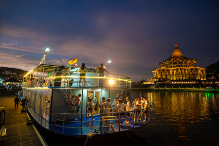 SARAWAK, MALAYSIA - SEPTEMBER 16, 2023: Sarawak River Cruise boat with a background of State Legislative Assembly building during a sunset cruise. One of the popular tourist attractions in Kuching.のeditorial素材