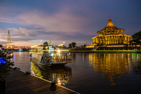 SARAWAK, MALAYSIA - SEPTEMBER 16, 2023: Sarawak River Cruise boat with a background of State Legislative Assembly building during a sunset cruise. One of the popular tourist attractions in Kuching.のeditorial素材