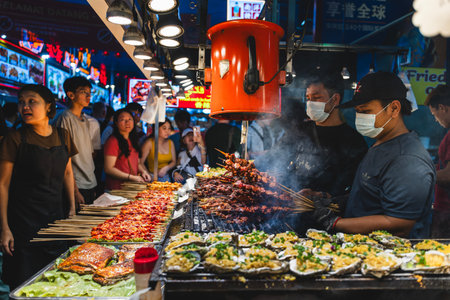 KUALA LUMPUR, MALAYSIA - DECEMBER 27, 2025: Hawkers at Jalan Alor prepare grilled and barbecued food...