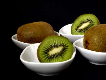 Fresh kiwi in white bowls on blackの写真素材
