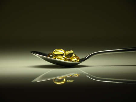 Golden pills on a spoonの写真素材