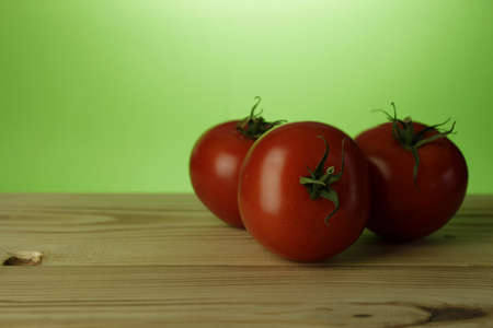Three tomatoes on a wooden tableの写真素材