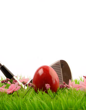 Red Easter egg on a green meadow with a golf clubの写真素材
