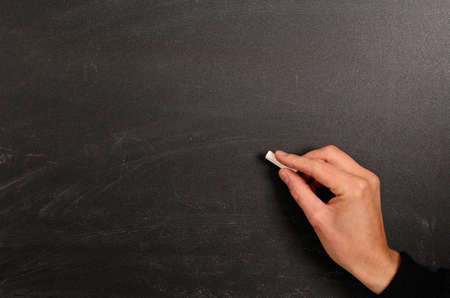 Hand writing with chalk on a blackboardの写真素材