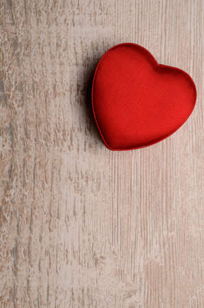 Red heart shaped gift box on a rustic wooden background with space for text or imageの写真素材