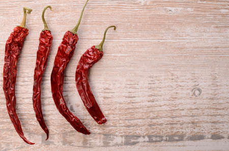 Four dried chilies on a rustic wooden