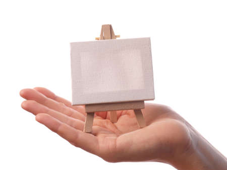 Female hand holding a wooden easel with a canvasの写真素材
