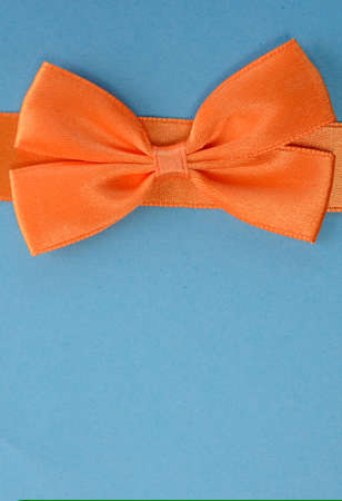 Orange bow on a blue background with space for text