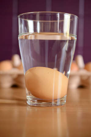 Fresh brown egg in a glass of waterの写真素材