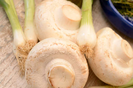White mushrooms on a wooden kitchen table with cooking ingredientsの写真素材