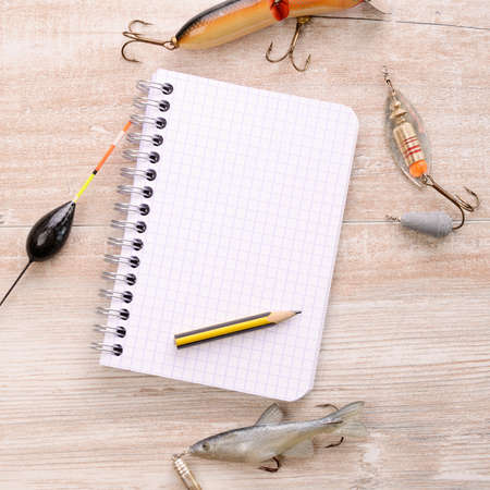 Fishing equipment with a blank notebook on a wooden tableの写真素材