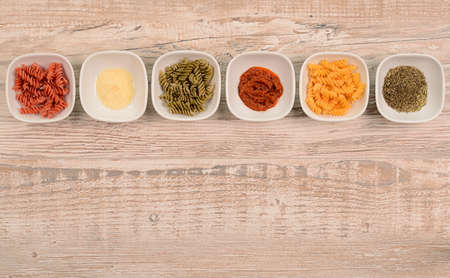 Pasta ingredients on a wooden background with space for textの写真素材