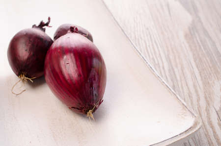 Red onions on a white wooden bowlの写真素材