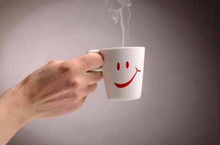 Hand holding a cup of coffee with steam