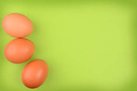Fresh brown organic eggs on a green background with space for text or imageの写真素材