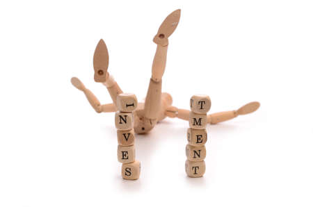 Financial concept with a fallen wooden puppet and dices eith the word investmentの写真素材