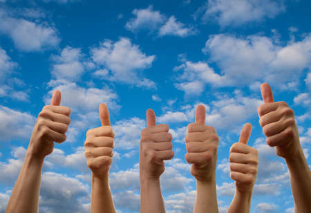 Six hands with thumbs up on a summer sky backgroundの写真素材