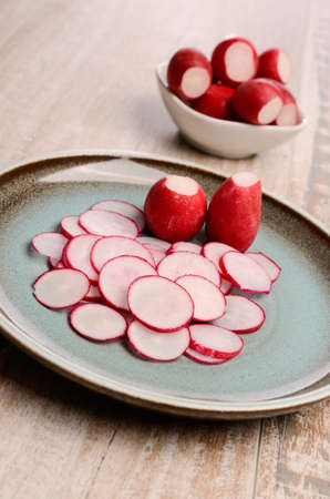 Fresh radishes on a rustic blue plate on a wooden tableの写真素材