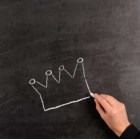 Hand drawing with chalk a crown on a blackboardの写真素材